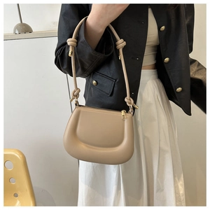 Detail of a khaki crescent shoulder bag featuring a unique knotted strap design