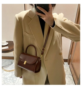 Detail of a vintage dark brown leather crossbody bag with a gold rectangular metal clasp