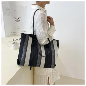 Dettaglio della grande borsa tote intrecciata con strisce e manici in pelle nera