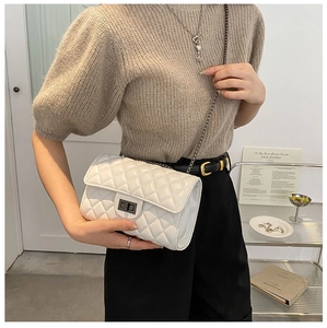 Detail of white quilted crossbody bag featuring silver turn-lock and elegant chain strap