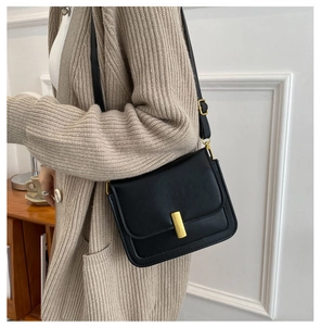 Détail d'un sac à bandoulière vintage en cuir noir avec boucle métallique dorée chic