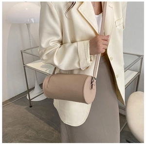 Detail of a chic beige cylindrical crossbody bag worn with an elegant suit