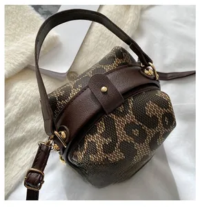 Detail of vintage leopard print round handbag showing brown fabric texture and gold hardware