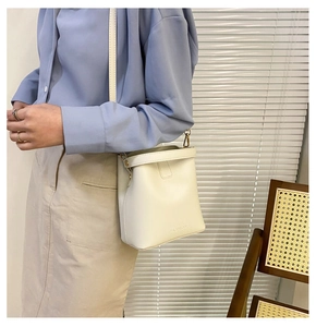 Detail of off-white leather bucket bag with FASHION logo and removable strap