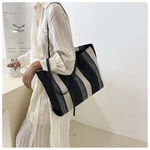 Vista dettagliata di una grande borsa tote in tela a righe indossata da una modella
