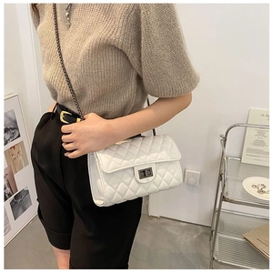 Detailed view of white quilted faux leather crossbody bag with chain strap and metal clasp