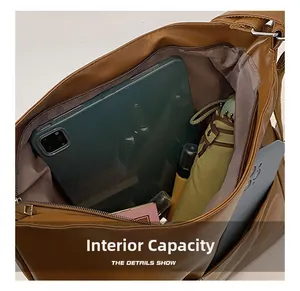 Vue macro de la capacité interne du sac en cuir PU marron avec tablette 11 pouces et objets