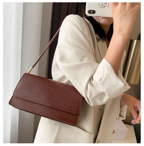 Detailed texture of dark brown crocodile embossed faux leather on a vintage shoulder bag