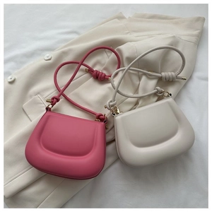 Detail of pink and beige saddle bags with 3D embossed texture and knotted shoulder straps