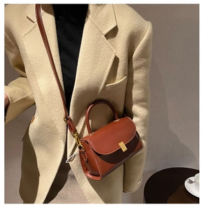 Detail of vintage brown leather handbag with gold rectangular buckle and top handle strap