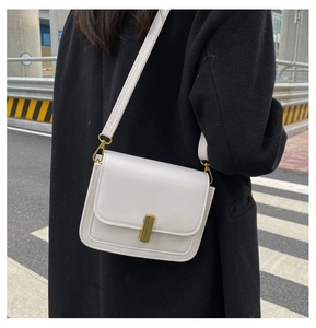 Gros plan d'un petit sac bandoulière blanc en cuir avec fermoir métallique doré chic