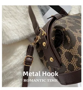 Close-up of golden metal hook and brown litchi grain strap on leopard print bag