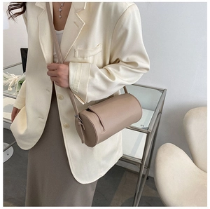 Chic beige cylindrical crossbody bag in smooth leather shown in a modern interior setting