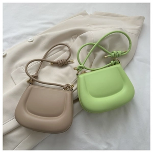Detail of minimalist saddle bags in brown and green with stylish knot shoulder straps