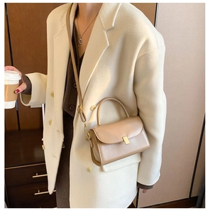 Detail of light brown leather crossbody bag with gold buckle and stylish top handle