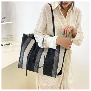 Dettaglio della grande borsa tote in tela a righe con spalline sottili in finta pelle