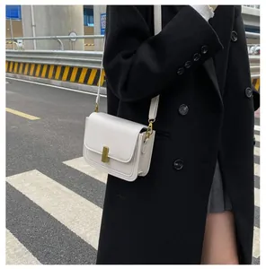 Photo de rue d'une femme portant un petit sac bandoulière blanc en cuir PU à boucle dorée