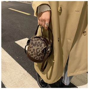 Detail of a vintage leopard print round crossbody bag styled with a khaki trench coat