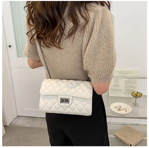 Detail of white quilted leather texture and silver twist lock on the crossbody chain bag