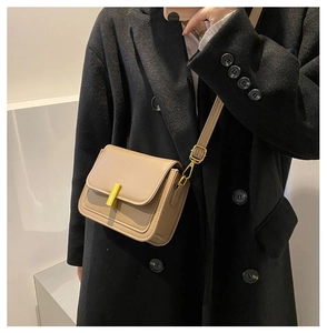 Petit sac bandoulière kaki sur manteau noir avec boucle en métal doré et sangle fine