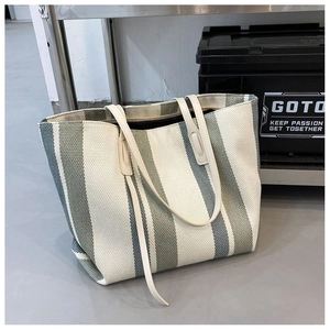 Dettaglio della borsa tote in tela a righe grigio-verdi con tessuto e manici in pelle