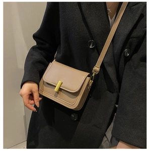 Détail du sac bandoulière kaki avec fermoir doré sur un modèle en manteau noir