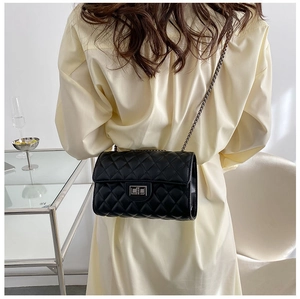 Rear view of a model wearing a black quilted crossbody bag with a metal chain strap
