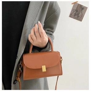 Detailed view of a vintage brown leather handbag featuring a stylish gold rectangular clasp