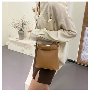 Detail view of brown leather bucket bag with fashion lettering and gold clasp