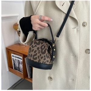 Detailed view of leopard print bucket bag with black leather trim and gold studs
