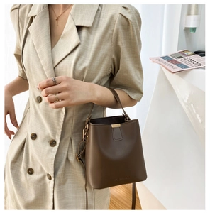 Detail of dark brown bucket bag with gold hardware and embossed fashion logo text