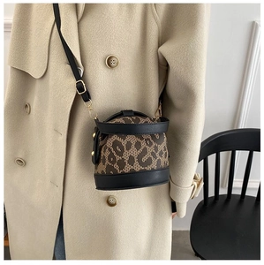 Detail of leopard print bucket bag with black leather trim and gold metal rivets