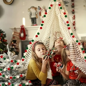 Close-up of red, green and white felt ball garland hanging on a Christmas tent and tree