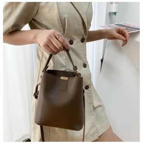 Detail of dark brown leather bucket bag featuring metal clasp and fashion embossing