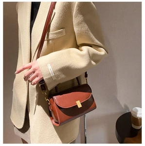 Close-up of vintage brown leather crossbody bag with elegant gold metal buckle detail