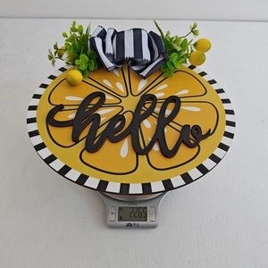 Detail showing round wooden lemon hello sign weight of 226.5g on a scale
