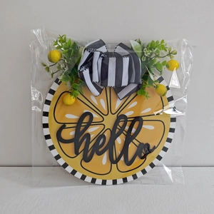 Detail view of Hello Lemon welcome sign with buffalo plaid bow and greenery in packaging