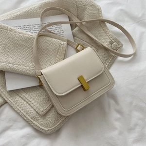 Petit sac bandoulière rétro en cuir crème avec boucle dorée sur fond de tweed beige