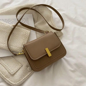 Sac bandoulière vintage en cuir marron avec boucle en métal doré sur fond de tissu doux