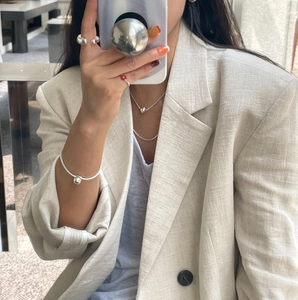 Minimalist silver irregular rings and matching jewelry styled with a beige linen blazer