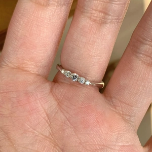 Detailed view of silver band ring featuring five sparkling round-cut stones worn on finger