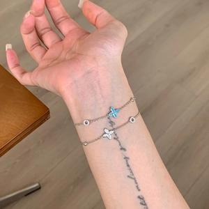 Silver dainty bracelets with sky blue and white clover charms on female wrist