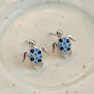 Macro shot of silver turtle stud earrings featuring deep and light blue micro-set zircons