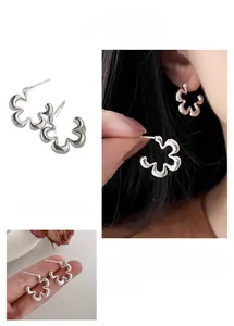 Detail shot of hollow flower stud earrings in silver finish with model ear styling