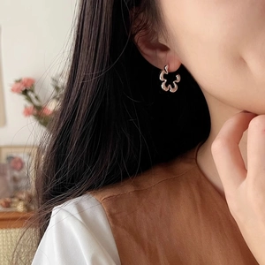 Minimalist silver wavy flower stud earrings with geometric petal design shown on a model