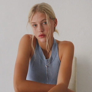 Minimalist adjustable silver bow tie necklace worn by a model on a knitted top