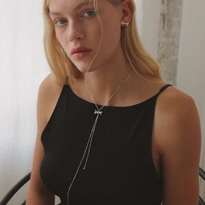 Adjustable silver bow pendant necklace and stud earrings set worn by a model
