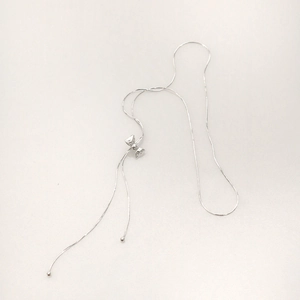 Detailed view of silver bow tie pendant with delicate tassel and snake chain