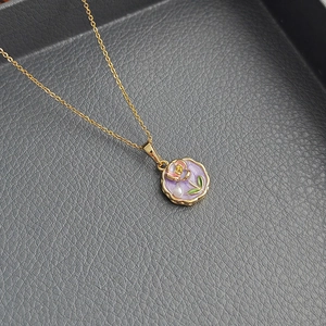 Golden necklace with a lavender enamel floral pendant and delicate white pearl accent
