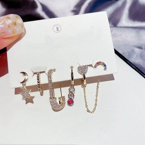 Detailed shot of gold earrings set featuring stars and moon with multicolored crystals
